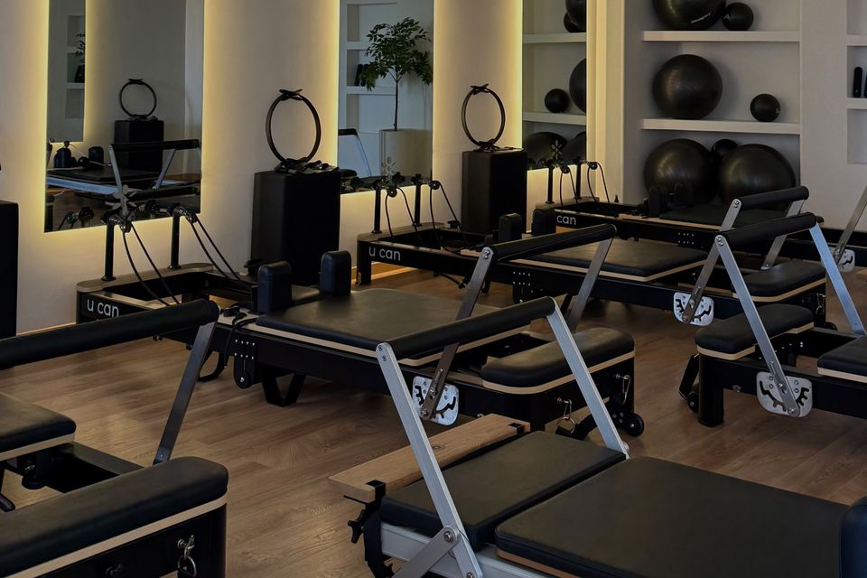 Sala de Plaza Marbella con reformers negros y espejos con luz cálida.